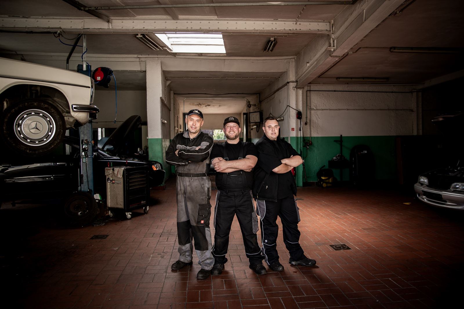 Das Team der Werkstatt Ismaning in der Halle mit Oldtimer auf der Hebebühne